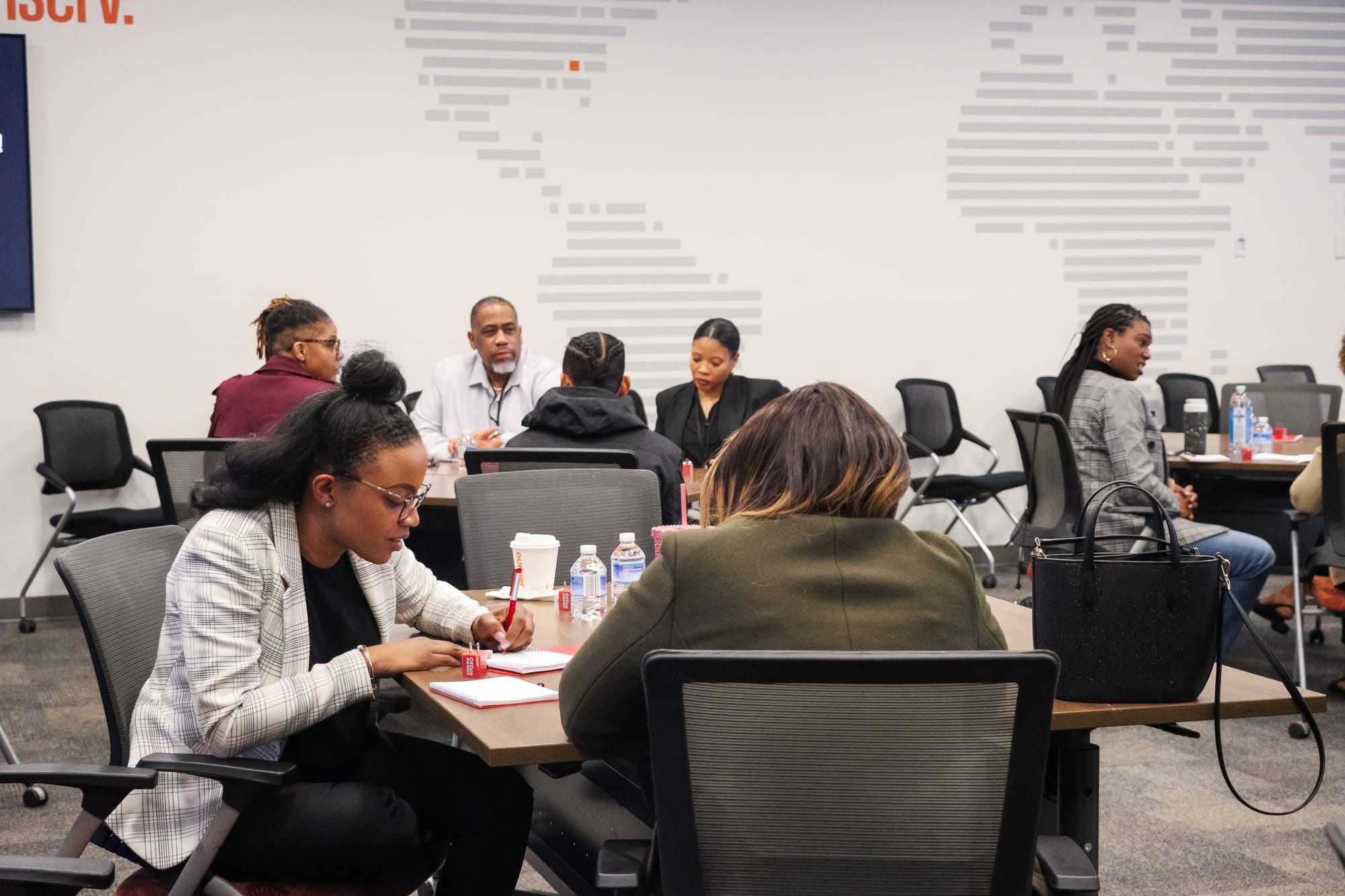 B.O.S.S. facilitators leading a working session with participants taking notes at tables